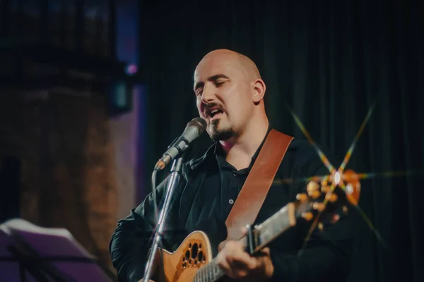 guitarist male playing guitar and singing a song at a concert