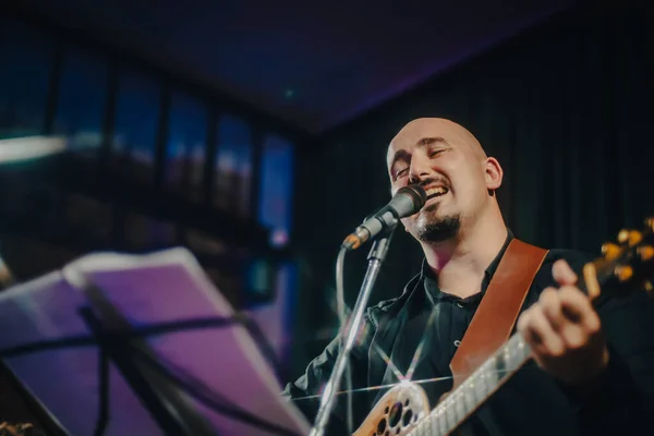 guitarist manplaying acoustic guitar and singing a song at a concert