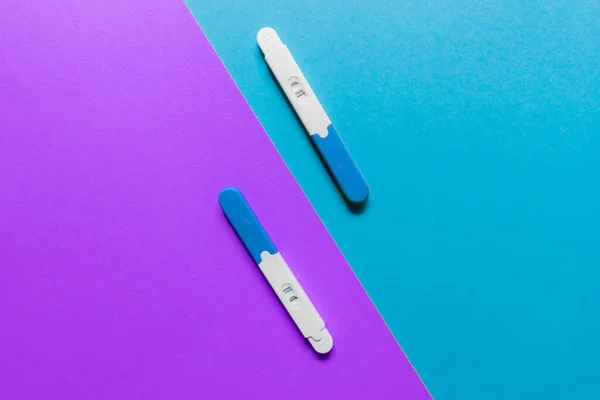 positive and negative pregnancy tests on blue and violet backgrounds