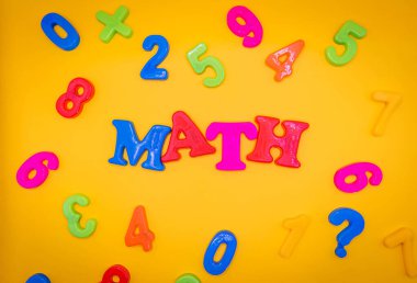 Word mathematic in bright color block letters on a yellow paper background. Space open for copy.