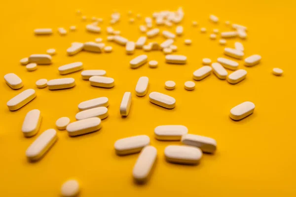 White prescription pills on yellow background close up