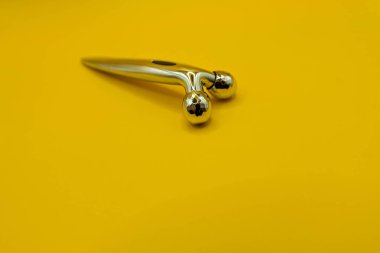 Modern metal face roller on yellow background side view