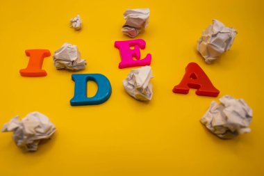 The word idea with colorful letters on yellow background side view