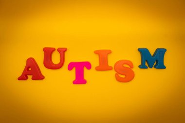Sarı arkaplanda renkli sözcük AUTISM