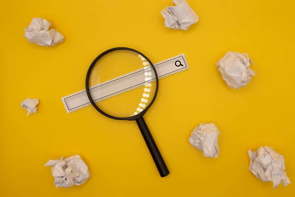 magnifying glass, web search tape and crumpled papers yellow background