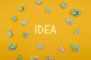 Sarı arka planda buruşmuş kağıt topları. Üst görünüm IDEA metni. Minimalist seo konsepti