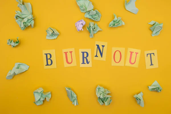 Word from letters burnout on yellow background. Concept of burnout. Flat lay.