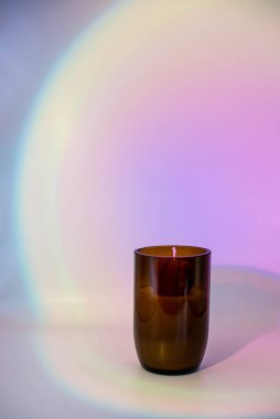 Kehribar camlı soya mumu pembe gradyan arka planda.
