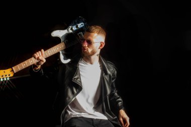 Deri ceketli ve pembe gözlüklü küstah bir rockçı omzuna gitar sarkıttı..