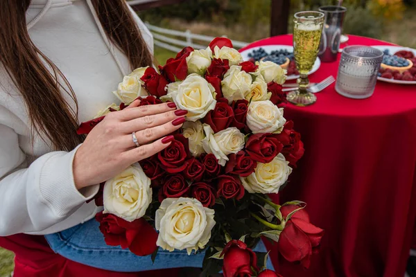 Will you marry me. She said yes. A girl\'s hand with wedding ring on a bouquet of red roses. Love concept. Marriage proposal. Closeup.