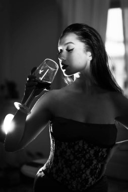 Kırmızı elbiseli kıvırcık bir esmer şarap içiyor..