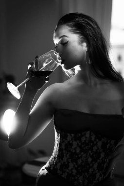 Kırmızı elbiseli kıvırcık bir esmer şarap içiyor..