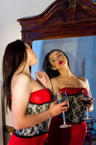 Kırmızı Elbiseli Çekici Genç Bir Kadın Bir Bardak Şarapla Aynaya — Stok fotoğraf