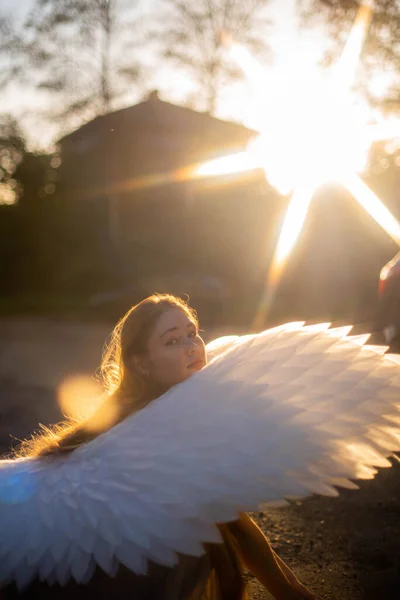 太陽の下で輝く大きな白い翼を持つ天使の女の子 いい秋の時間だ 女の子はスクワットし カメラを見て — ストック写真