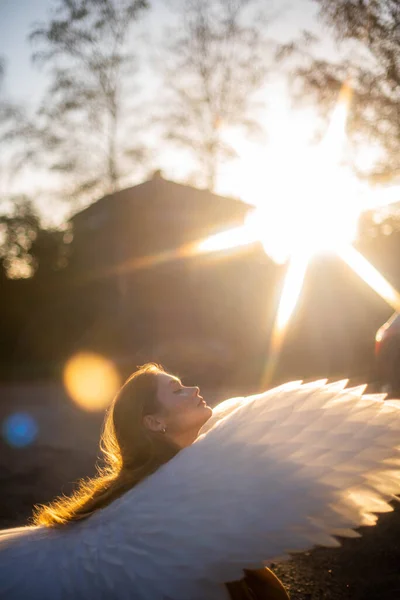 太陽に面した少女の肖像画 背中には大きな白い翼がある 女の子は座って太陽の下で日光浴 — ストック写真