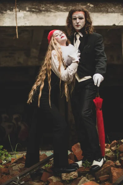 メイクの赤いベレー帽の黒と白のスーツの女の子は 黒いスーツと帽子の背の高い若い男にもたれています お祝いハロウィン — ストック写真