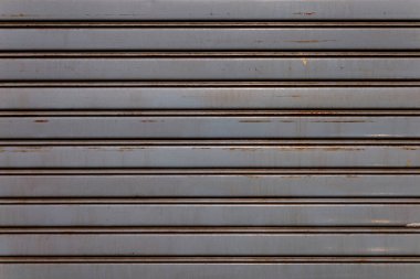 perpendicular view of a steel shop shutter ruined and rusted by time