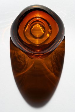 retro style amber glass ashtray dating back to the 60s on a white background with colored obra and reflections