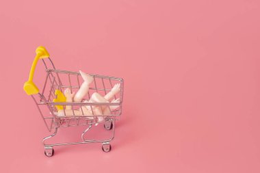 Kukla eller pembe arka planda bir süpermarketten tramvayı itiyor, minimalizm kavramı.