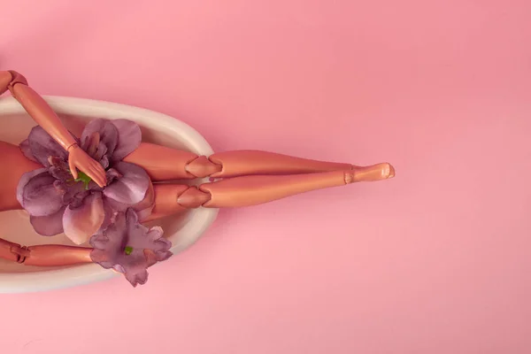 Dolu bir küvette pembe arka planda yıkanan bebek. Yaratıcı asgari güzellik yaz konsepti. Yan görünüm