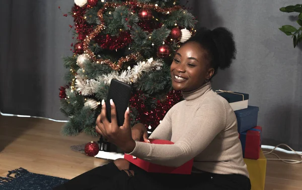 Young happy and worried woman calling her boyfriend on smartphone video call to ask him where he is and why he late on the Christmas evening party and New Year Eve she is waiting for him with gifts