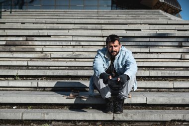 Genç, hasta, bunalımlı, evsiz bir adam alışveriş merkezinin merdivenlerinde oturmuş, kendisine ve ailesine iş kaybından sonra yemek almak ve evi kaybetmek için yalvarıyor. Evsizlik sosyal konsepti.