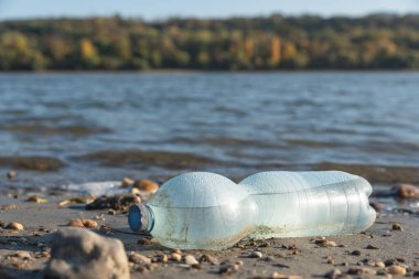 Büyük şehrin plajına çöp döküldü. Kullanılmış kirli plastik şişe. Kirli deniz kumlu kıyısı. Çevre kirliliği. Ekolojik bir sorun. Arkaplanda dalgalar hareket ediyor