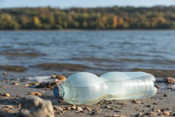 Büyük şehrin plajına çöp döküldü. Kullanılmış kirli plastik şişe. Kirli deniz kumlu kıyısı. Çevre kirliliği. Ekolojik bir sorun. Arkaplanda dalgalar hareket ediyor