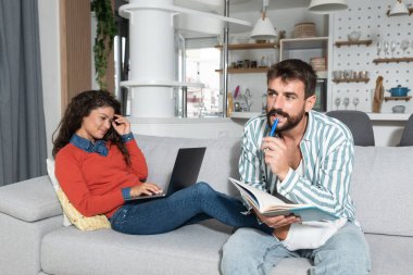 Evden çalışan küçük işletme sahipleri. Evli bir adam ve bir kadın evdeki koltukta oturmuş yeni ticari fikirler ve sahip oldukları internet sitesi ve şirket stratejileri üzerinde çalışıyorlar. Seçici odak.