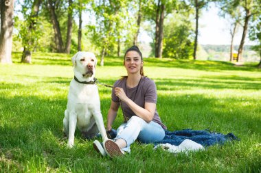 Parkta, evcil köpeği beyaz Labrador Retriever 'la birlikte ona iyi bir hayat ve sevgi vermek için evcil hayvan barınağından evlat edindiği güzel bir kadın. Evlatlık yavrusuyla eğlenen dişi hayvan sever..