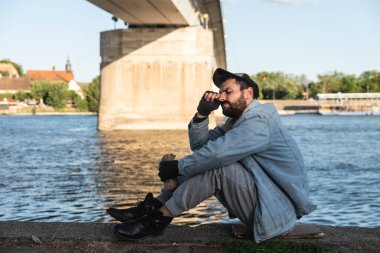 Genç, aç, çaresiz evsiz, terk edilmiş ve üzgün bir adam dışarıda oturuyor. İşsiz, hasta, çaresiz bir erkeğin yardıma ihtiyacı var. Evsizlik sosyal meseleler kavramı.