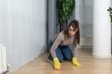 Genç ev sahibi kiraya verdiği daire için büyük bir temizlik yapıyor. Kiraladığı yeni kiracıların temizlenmesi için. Yerleri ovuşturan genç kız ya da kadın.