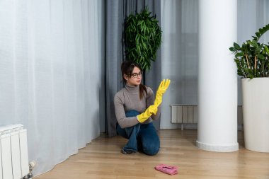 Genç ev sahibi kiraya verdiği daire için büyük bir temizlik yapıyor. Kiraladığı yeni kiracıların temizlenmesi için. Yerleri ovuşturan genç kız ya da kadın.