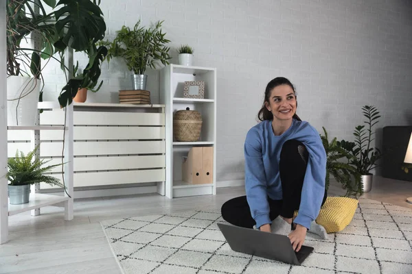 Nilüfer pozisyonunda oturan mutlu ve çekici genç bir kadın antrenörle internetten yoga kursuna başlıyor ya da uzaktan antrenör olarak Webinar seansı yapıyor..