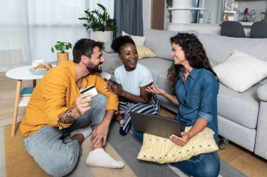 Ağaç mutlu genç serbest iş ortakları ve sahipleri, evde oturan arkadaşlar mutlular çünkü yeni internet mağazalarının internet sitesindeki kredi kartlarıyla online alışveriş yapmayı denediler..