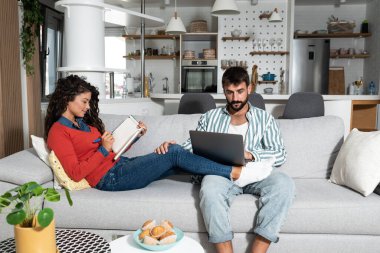 Evde oturan genç çift internette spor bilgisayarlarına bahis oynuyor ve kadınlar da ev ekonomisini yazıyor ve hesaplıyor. Karı koca vergisi hesapları..