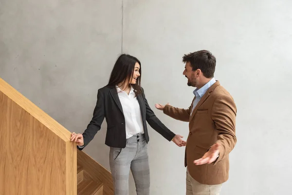 Young business people met on the staircases in the office building woman congratulates man colleague on job promotion. Successful happy workers talking not seeing long tame when she is promoted.
