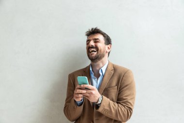 Ofisteki cep telefonuna bakarken gülümseyen bir iş adamı. Şirkette daha yüksek bir mevkiye terfi ettiğini söyleyen mutlu işçi gülümsemesi..