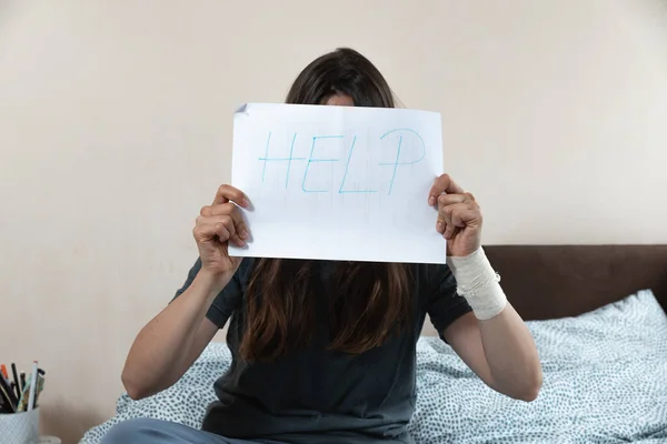 手拿着绷带的年轻而不幸的受伤妇女用求助字条遮住了她的脸 沮丧的女性因抑郁和焦虑而感到害怕和压力 需要帮助 — 图库照片