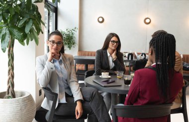 Bir grup serbest çalışan genç insan kafeteryada oturmuş, küçük bir şirketin eşit ortaklar olarak açılması ve tam zamanlı iş için fikirleri olan genç insanları işe almaları konusunda toplantı yapıyorlar..