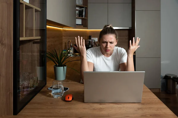 Young stressed student or freelancer business woman having anxiety attack and migraine from bad internet connection while she working online on her laptop computer in home office.