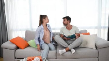 Happy pregnant woman surprise unhappy man with positive pregnancy test. Boyfriend is frustrated when his girlfriend show him positive test result and that they will have a baby.
