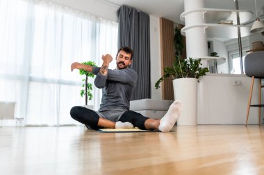 Young man rehabilitation exercise at home after car crash accident. Recovery workout of young guy with yoga training poses for stretching the muscles. Physical therapy exercising