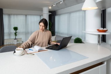 Young college student doing homework at home on her laptop. Girl reading and doing research for her study online on computer for school project about abortion.