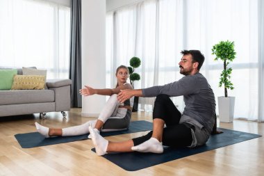 Genç aktif çift evlerinde yoga minderleri kaslarını esnetirken egzersiz yapıyor. Karı koca iş yerinde her gün stresi azaltmak için antrenman yapıyor..