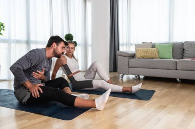 Genç aktif çift evlerinde yoga minderleri kaslarını esnetirken egzersiz yapıyor. Karı koca iş yerinde her gün stresi azaltmak için antrenman yapıyor..