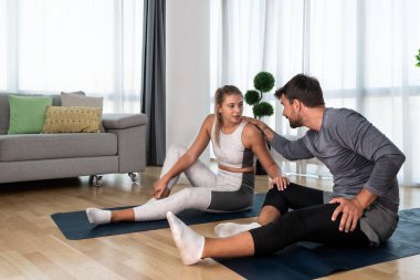 Genç aktif çift evlerinde yoga minderleri kaslarını esnetirken egzersiz yapıyor. Karı koca iş yerinde her gün stresi azaltmak için antrenman yapıyor..