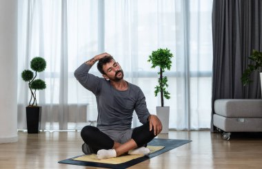 Young man rehabilitation exercise at home after car crash accident. Recovery workout of young guy with yoga training poses for stretching the muscles. Physical therapy exercising