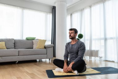 Young man rehabilitation exercise at home after car crash accident. Recovery workout of young guy with yoga training poses for stretching the muscles. Physical therapy exercising