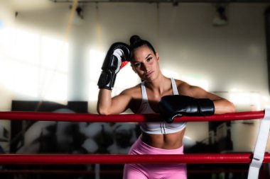 Genç terli boksör kadın ya da kız boks ringinde boks eldivenleriyle gelecekteki şampiyon egzersiz kutusu talimi yapıyor. Çekici kadın boksör dövüş antrenmanı..